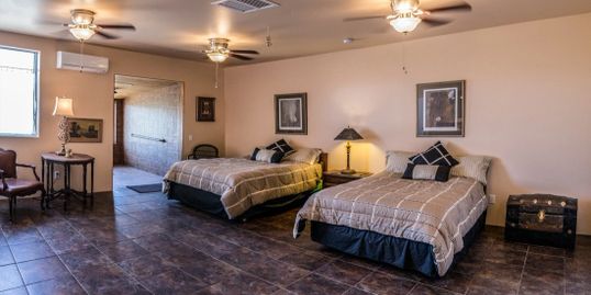 A room with two beds and lamps on the wall.