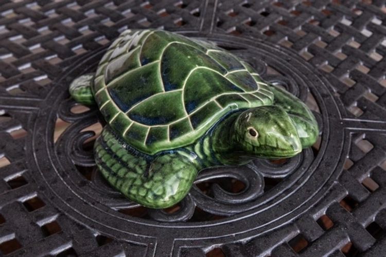 A green turtle statue sitting on top of a black table.