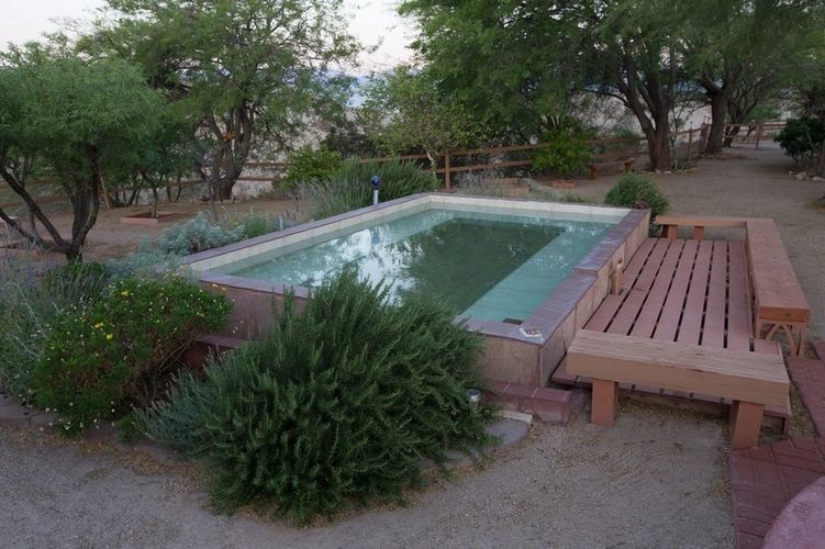 A pool in the middle of a yard with trees.