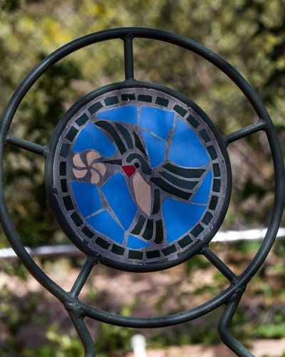 A blue and black clock with a bird on it