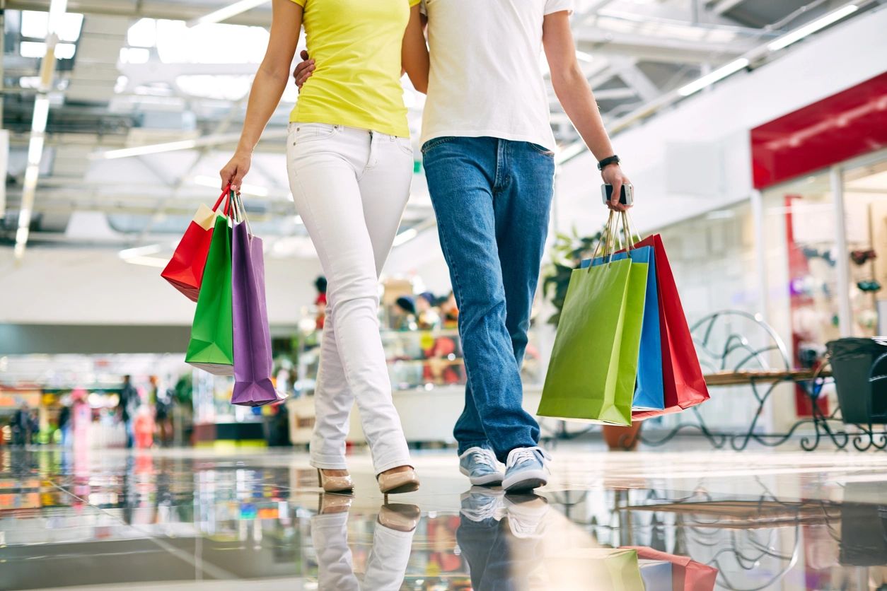 A man and woman holding shopping bags while walking.