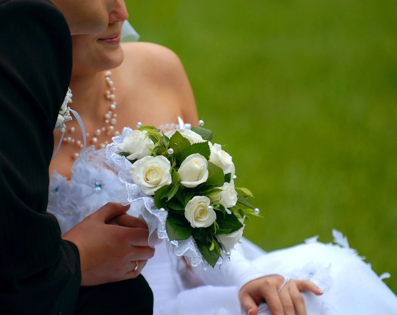 A bride and groom holding hands while standing on the grass.