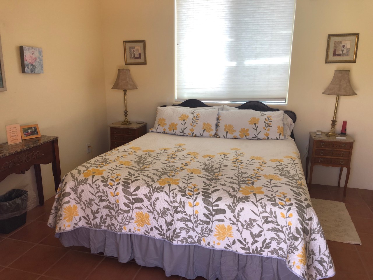 A bed room with a neatly made bed and two tables