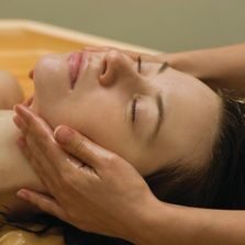 A woman getting her face washed by a masseuse.